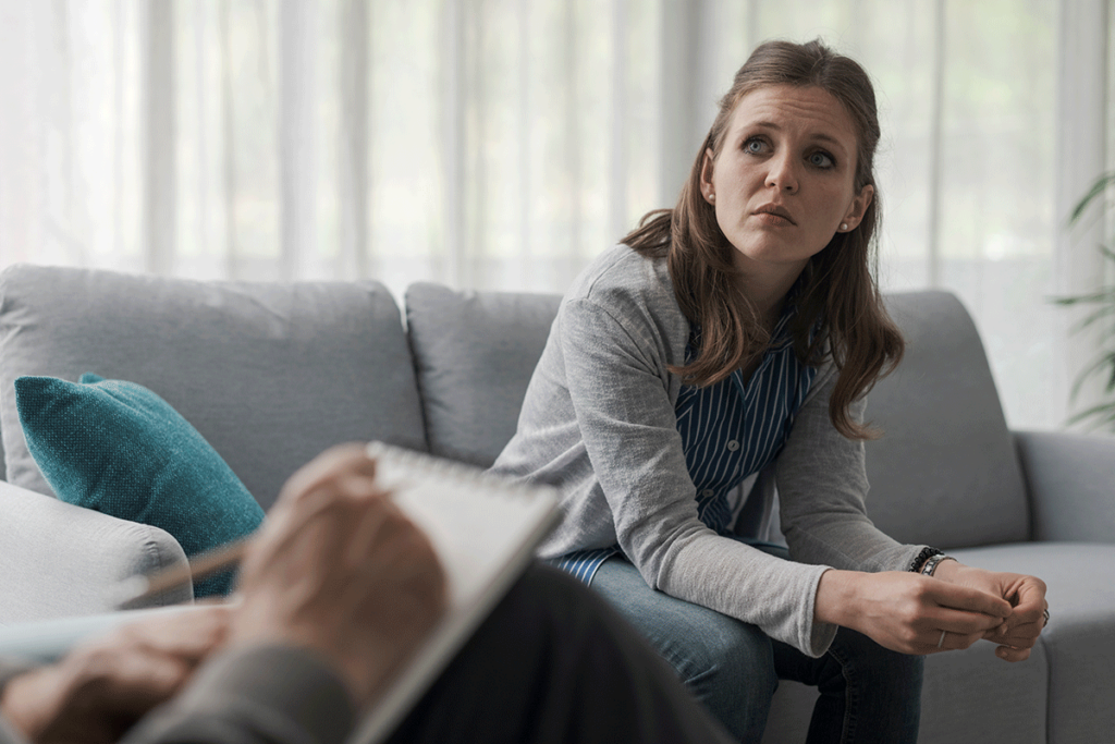a person sits on a couch asking a therapist about medication assisted treatment for alcohol