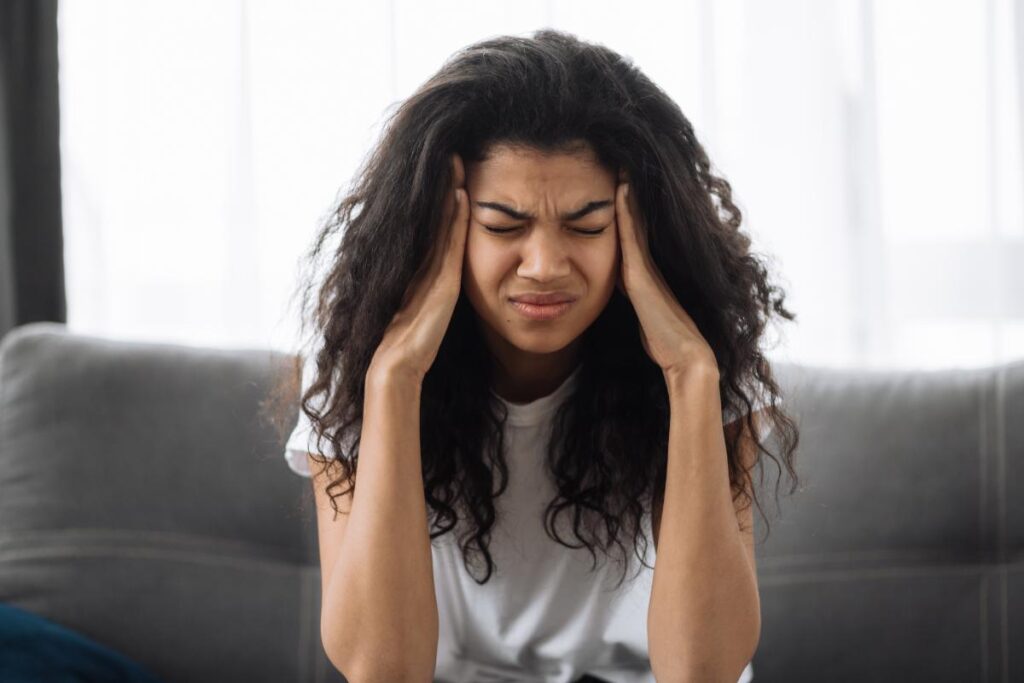 a person holds their head, possibly struggling with signs of a relapse