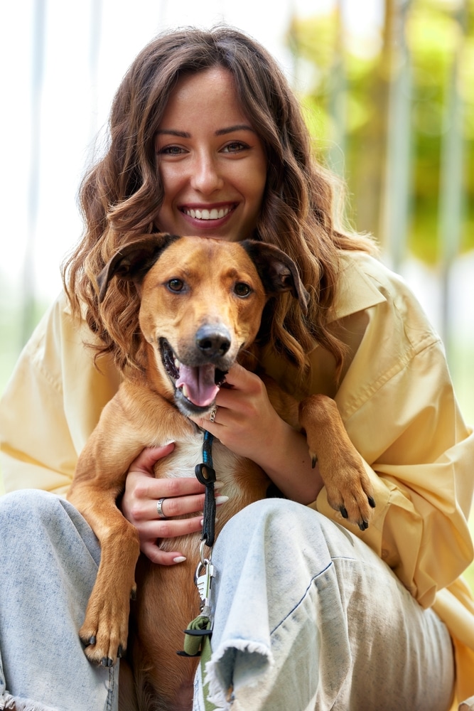 A smiling woman holds a dog.